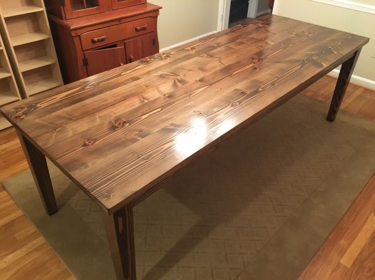 8ft long dark walnut dining room table with tapered legs on a rug